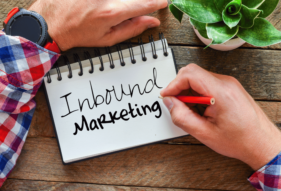 Inbound marketing written on a notepad beside a plant and a wooden table.